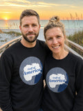 Garrett and Savannah wearing matching black Gulf of America retro map sweatshirts on a beach boardwalk at sunset