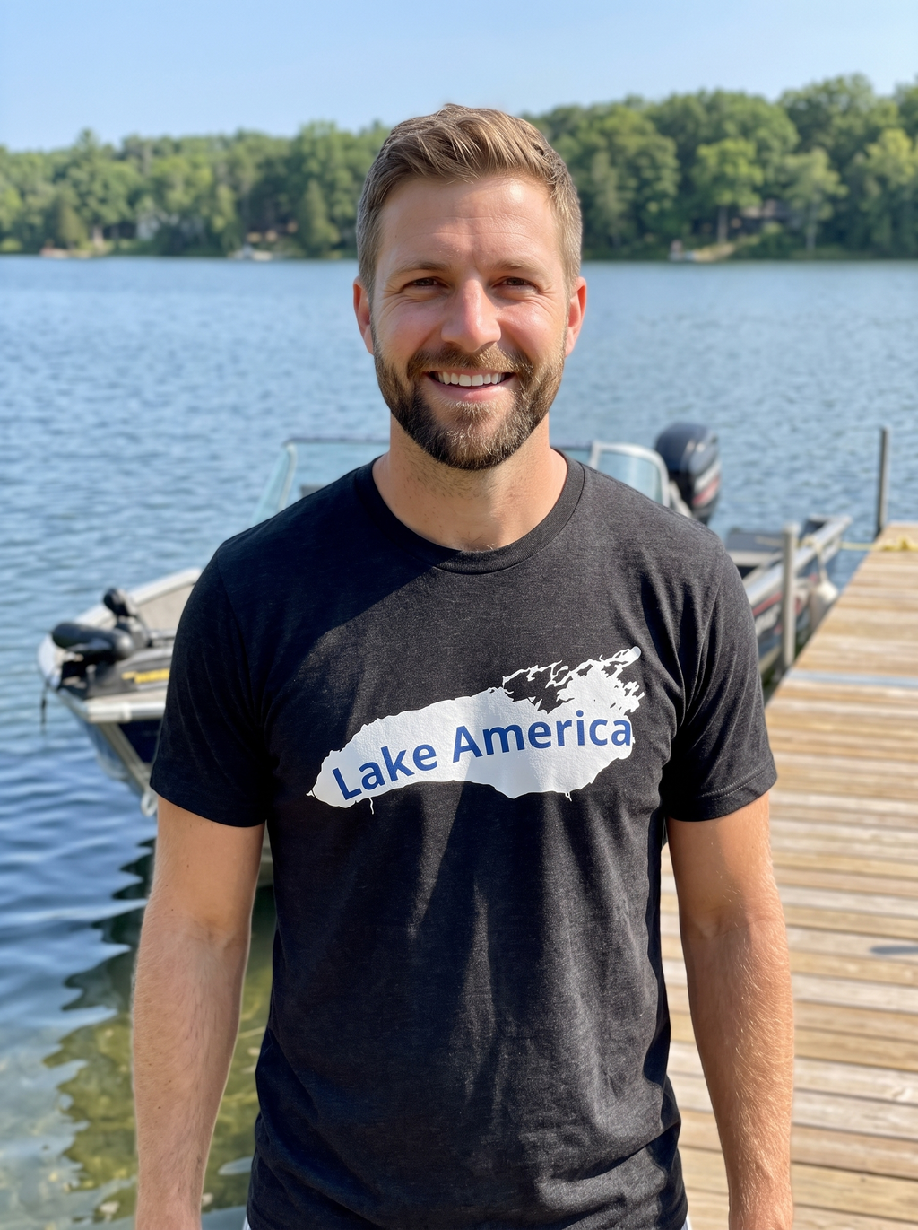 Man smiling on a wooden dock by a lake wearing the Lake America retro tee in black heather