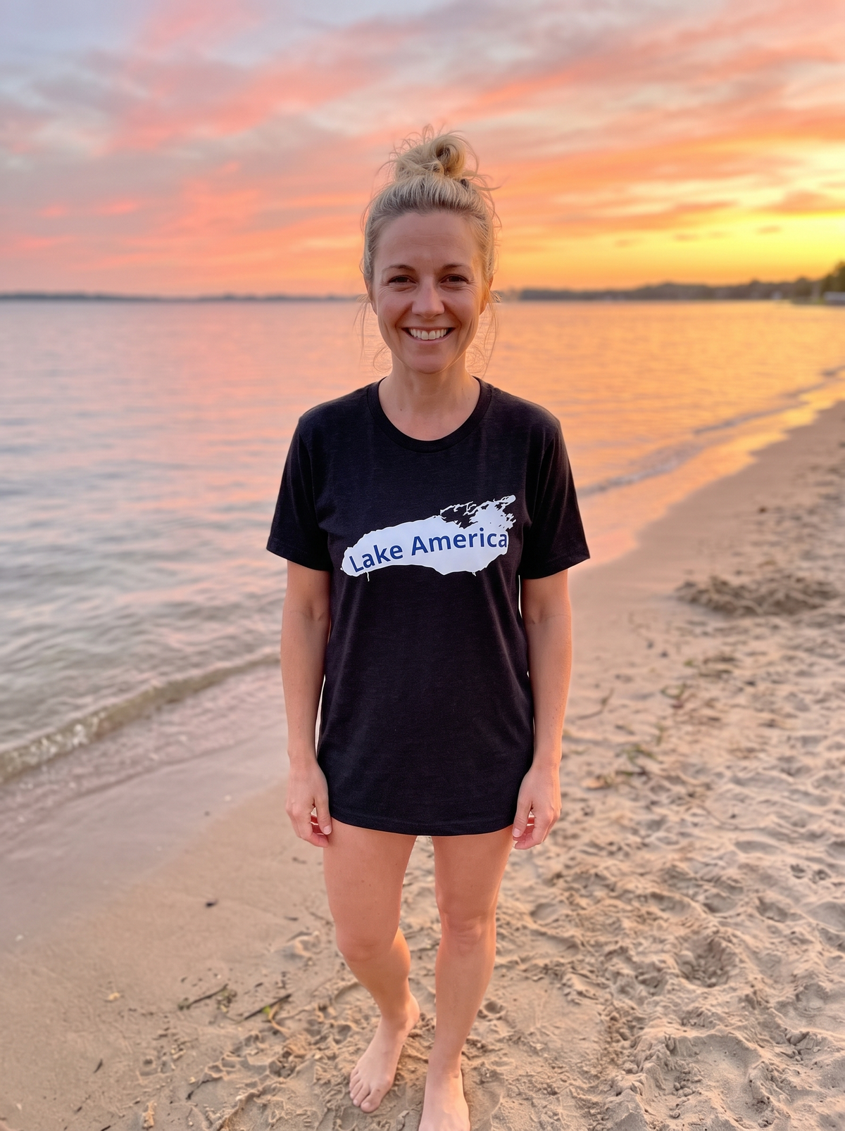 Woman smiling on a sunset beach wearing the Lake America retro tee in black heather