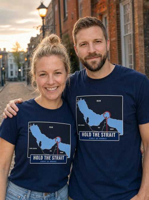 Couple in navy Hold the Strait tees with a Strait of Hormuz map print, on a brick street at sunset