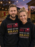 Garrett and Savannah smiling in matching black Ho Ho Home of the Brave Christmas hoodies by a backyard fire pit under string lights at dusk (AI-generated photo)