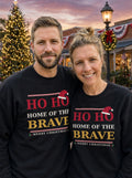 Garrett and Savannah smiling in matching black Ho Ho Home of the Brave Christmas sweatshirts in a town square at dusk beside a lit Christmas tree (AI-generated photo)