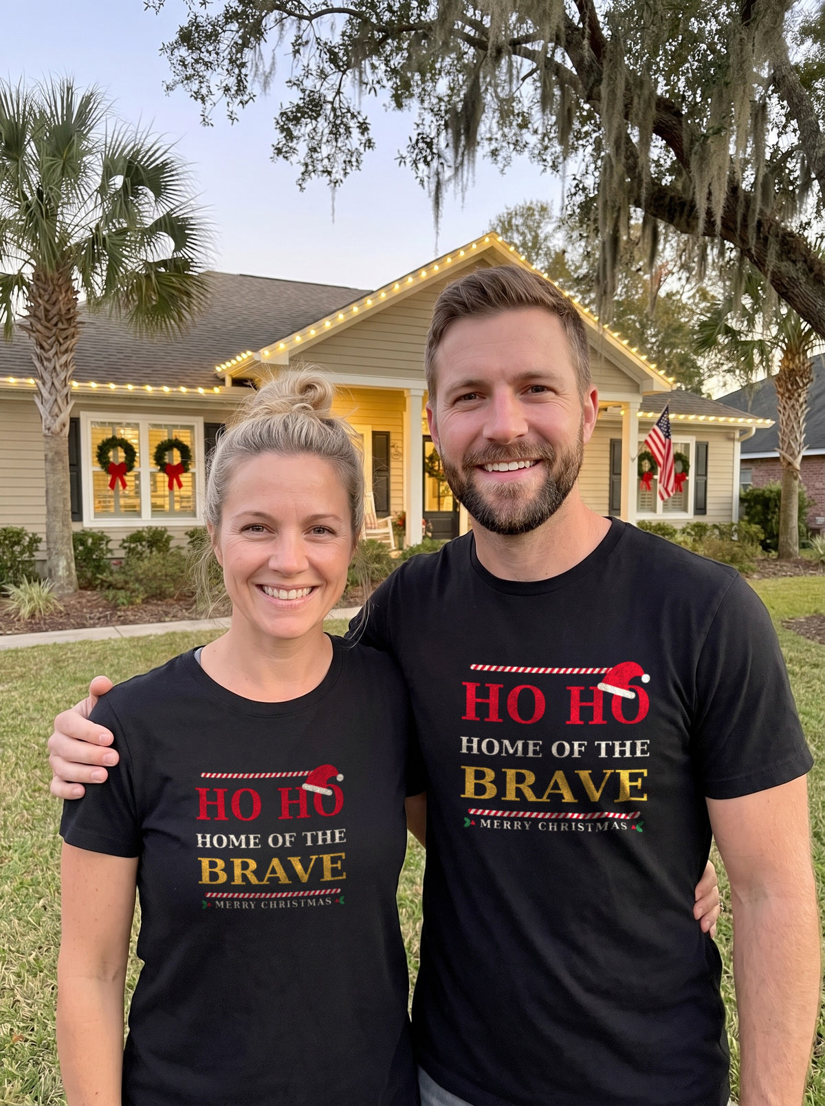 Garrett and Savannah smiling in matching black "Ho Ho Home of the Brave" Christmas Patriot tees on a front lawn with holiday wreaths