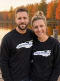 Couple in black Lake America crewneck sweatshirts standing on an autumn lakeside dock