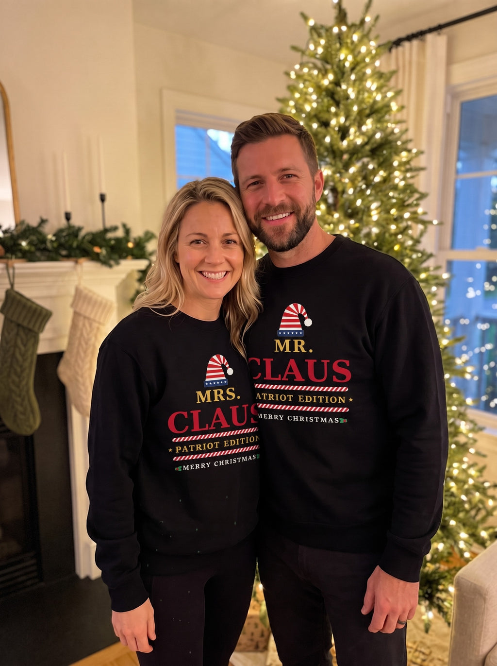 Couple in matching black Mr. Claus and Mrs. Claus patriotic Christmas sweatshirts by a lit Christmas tree