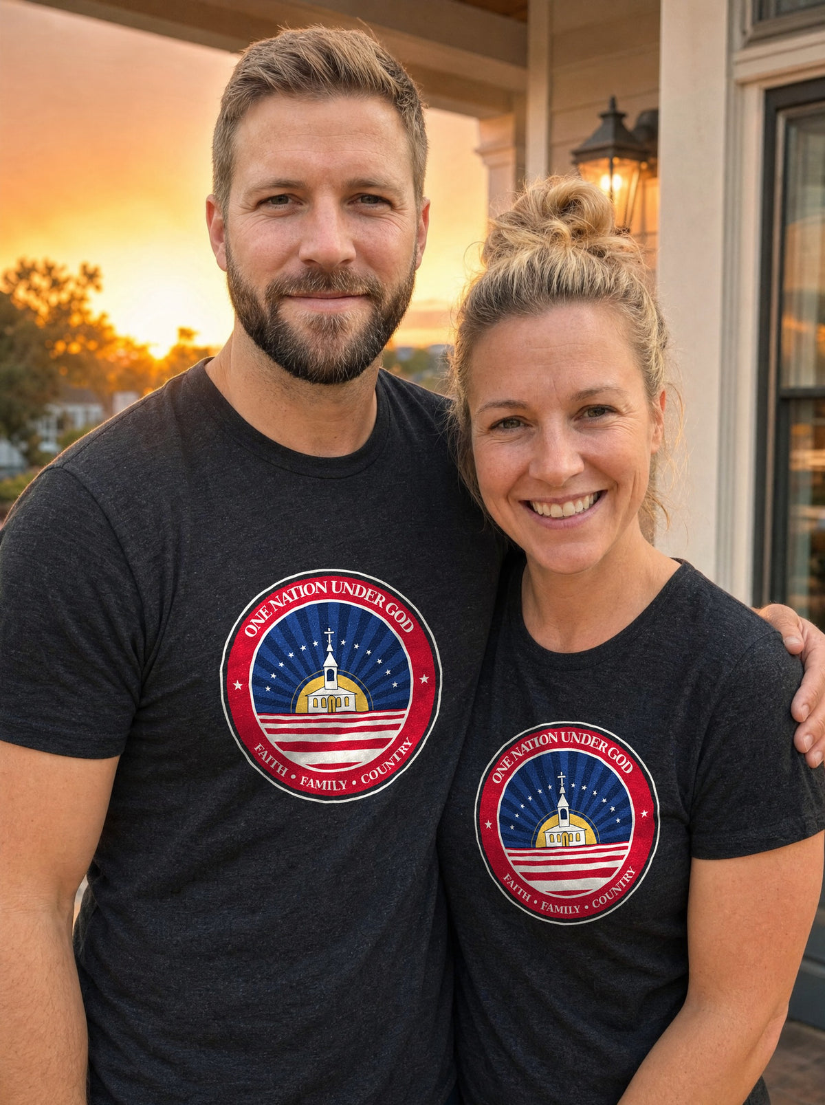 Garrett and Savannah smiling on a porch at sunset, both wearing black heather tees with the One Nation Under God badge