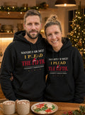 Garrett and Savannah in matching black I Plead the Fifth Christmas Edition pullover hoodies with a Santa hat graphic, standing at a kitchen island with hot cocoa and sugar cookies