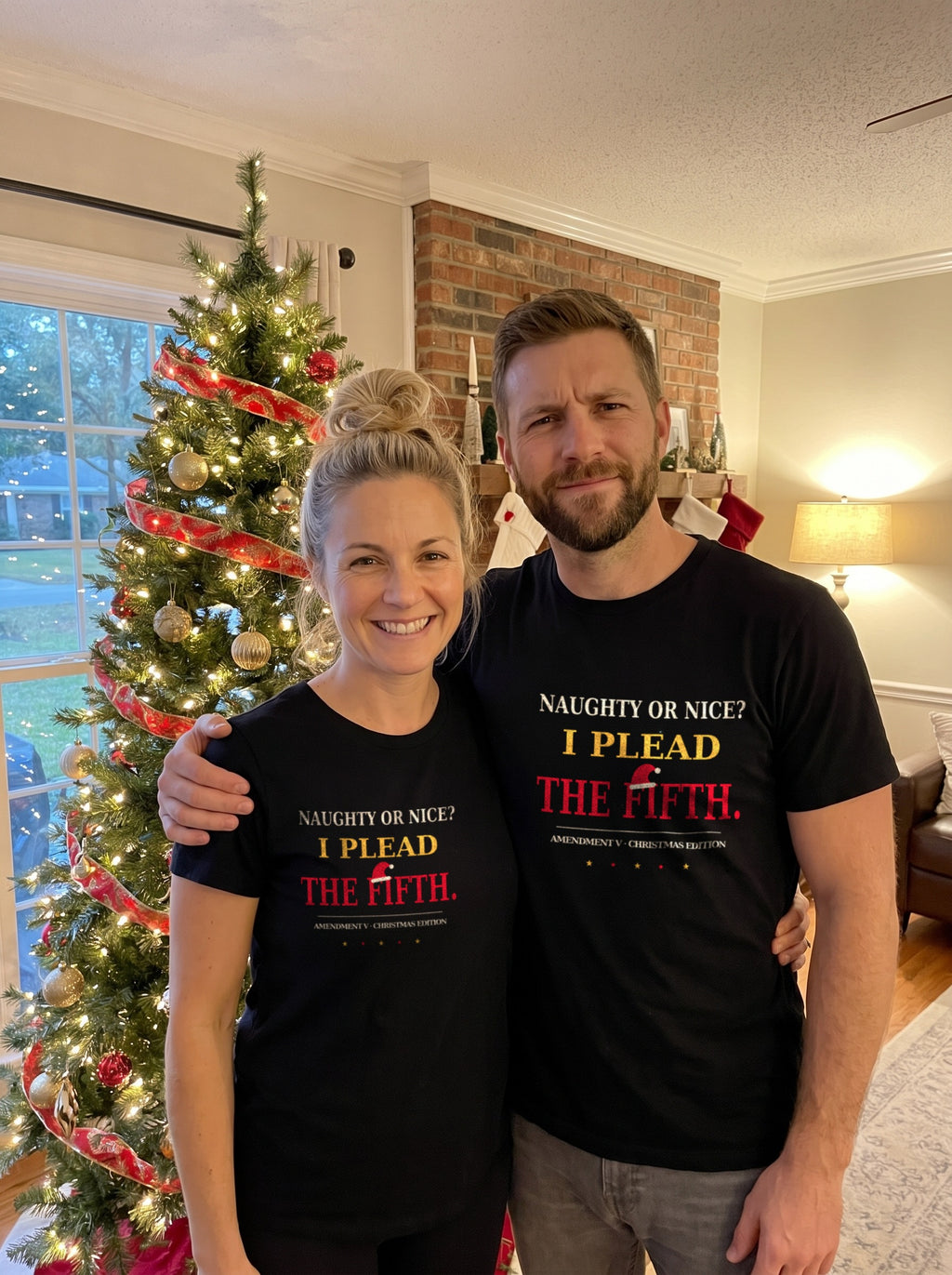Garrett and Savannah in matching black "Naughty or Nice? I Plead the Fifth" Christmas Patriot tees in front of a decorated Christmas tree