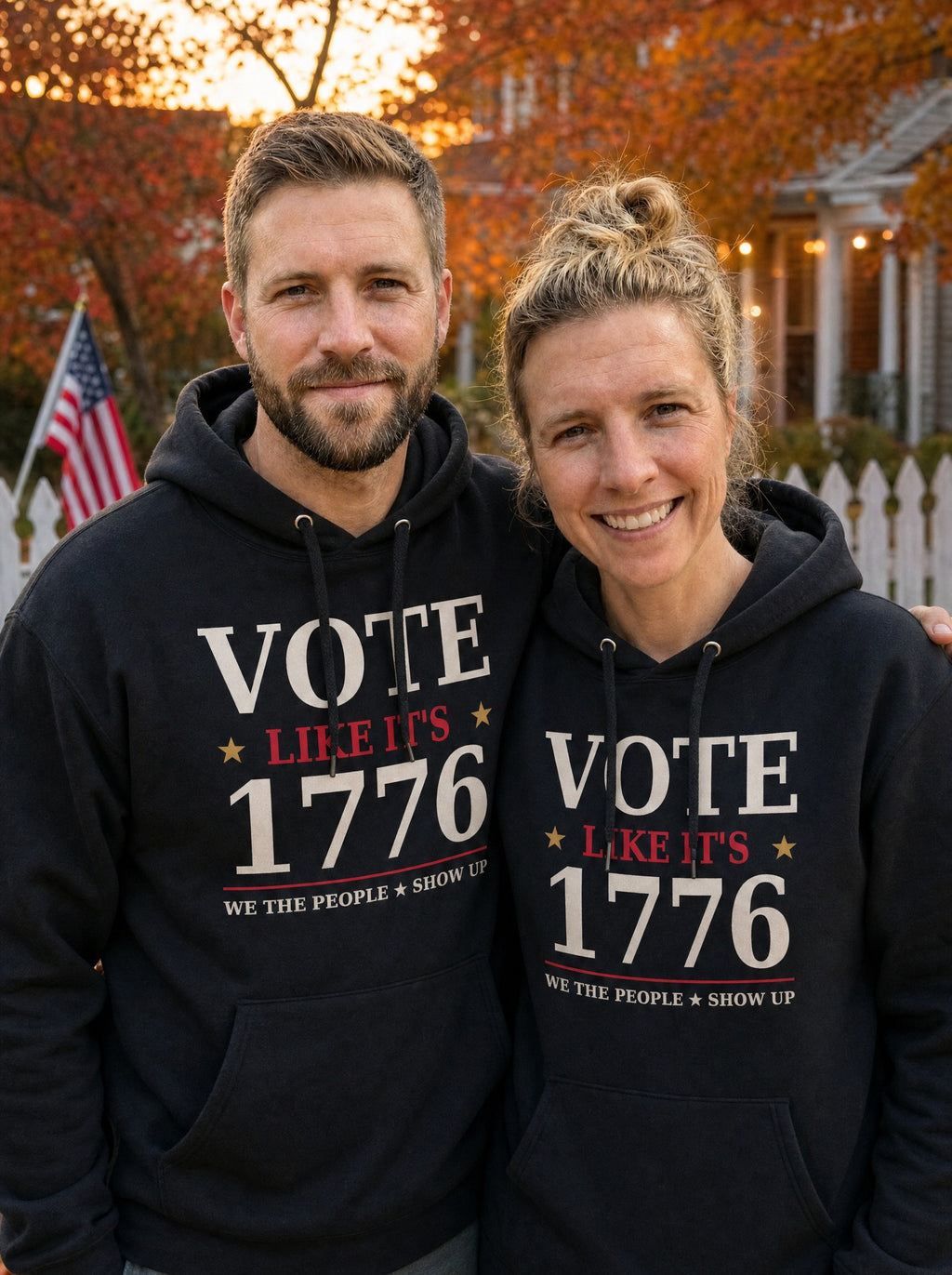 Garrett and Savannah in matching black Vote Like It's 1776 pullover hoodies in a backyard with a white picket fence and American flag at autumn dusk
