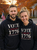 Garrett and Savannah in matching black Vote Like It's 1776 pullover hoodies in a backyard with a white picket fence and American flag at autumn dusk